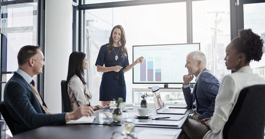 Woman presenting bar graph data to colleagues in a conference room