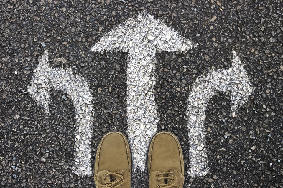 Man's loafers standing on arrows drawn on ground