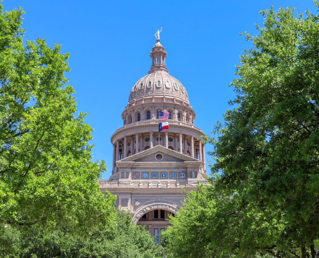 Texas state capitol with trees and blue sky
