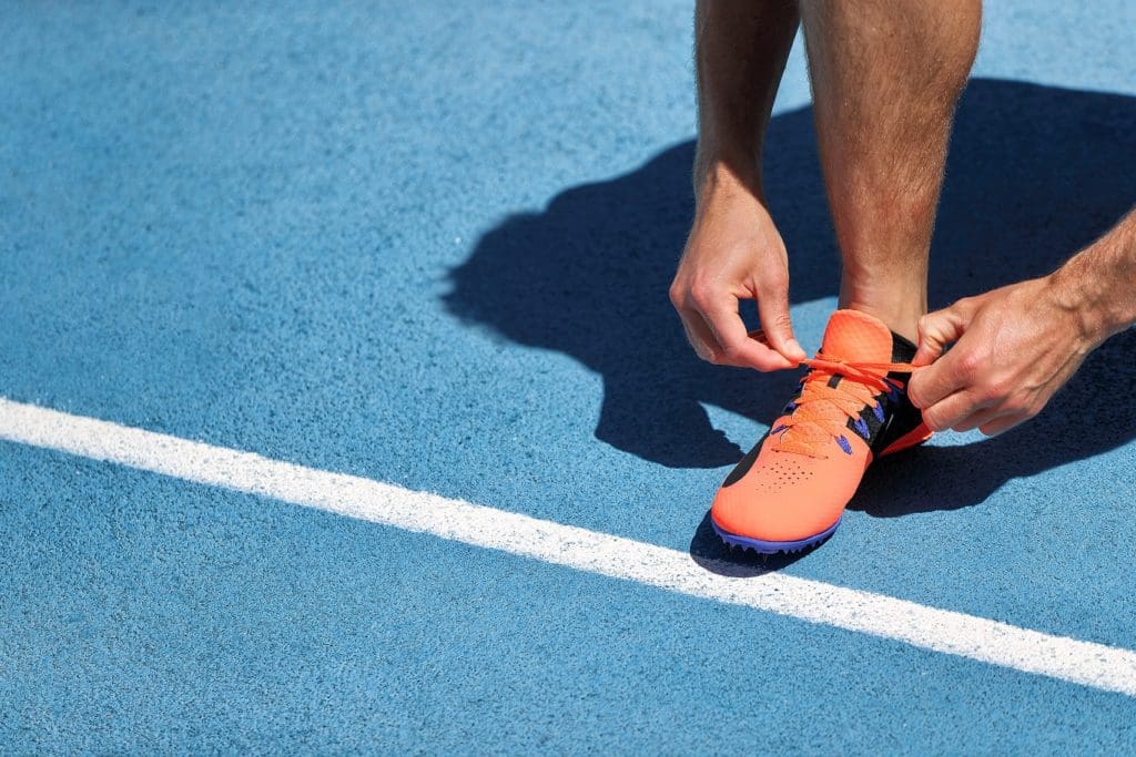 runner tying orange shoe in preparation for a race