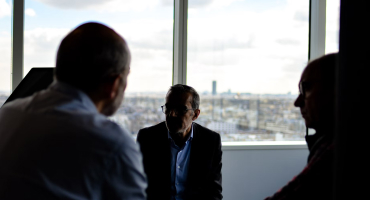 People in meeting space in front of a window overlooking the city
