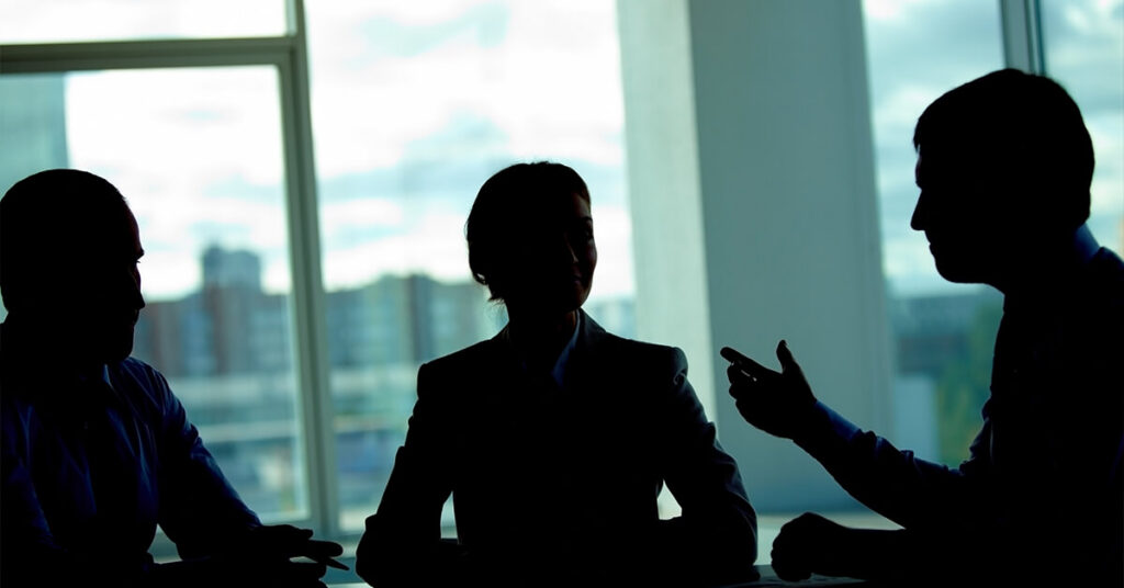 People in meeting space in front of a window overlooking the city